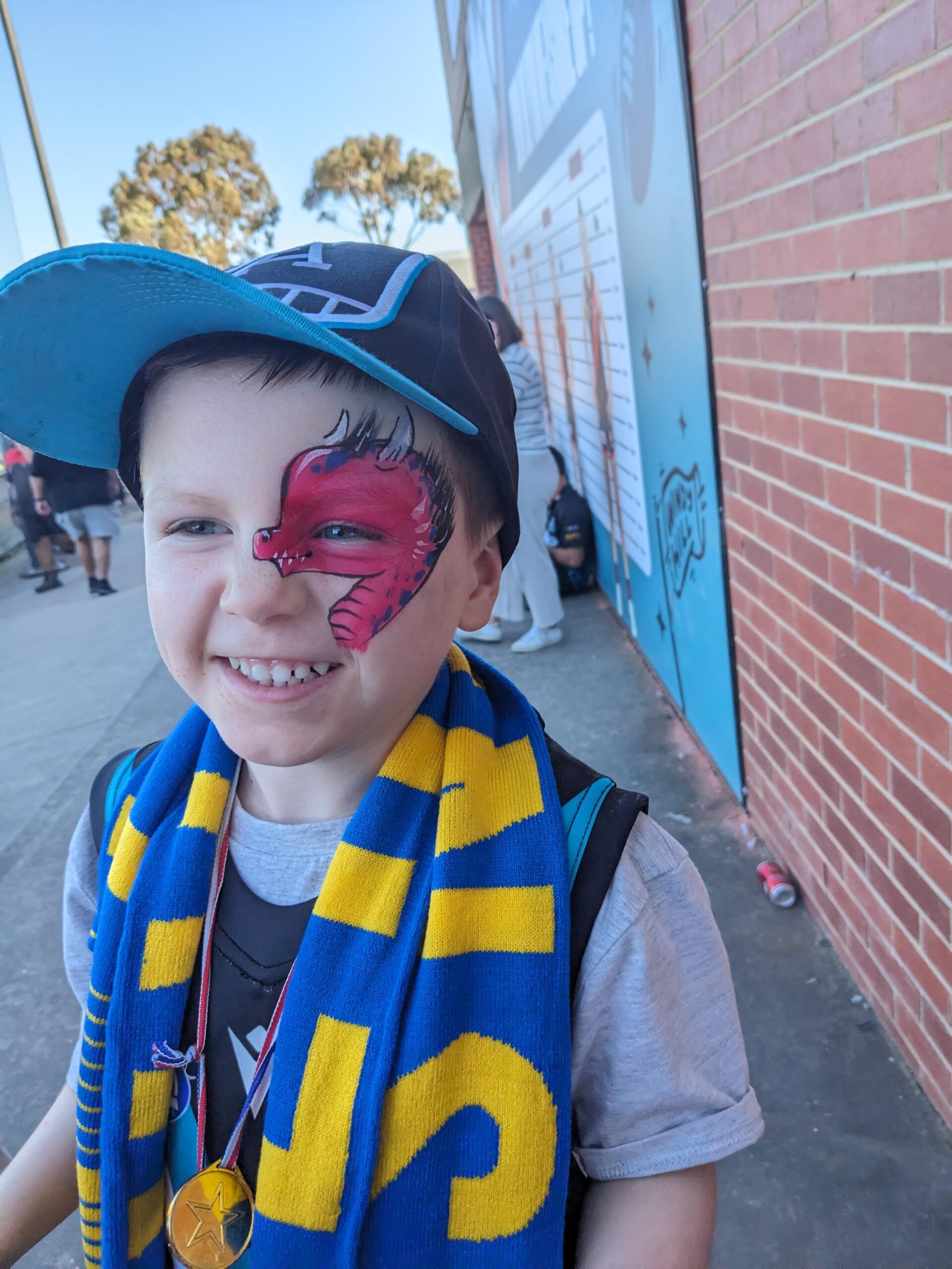 face painting australia red dinosaur face paint design on boy at sports game melbourne australia affordable face painting near me